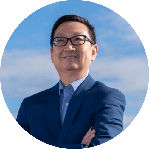 Person wearing glasses with arms crossed against a blue sky background